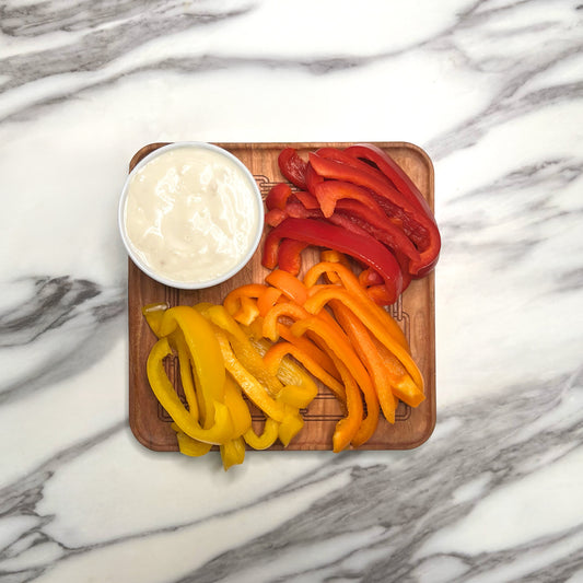 Cherry square plate with a trio of bell peppers and a cup of ranch.