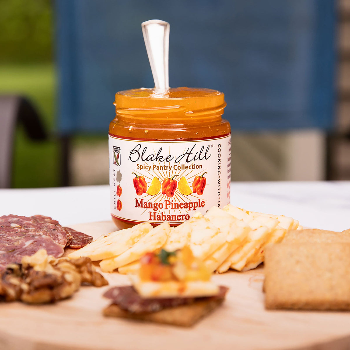 Jar of Blake Hill Mango Pineapple Habanero on a charcuterie board with various foods.