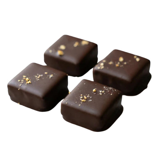 Four chocolate candies with gold sprinkles on a white background