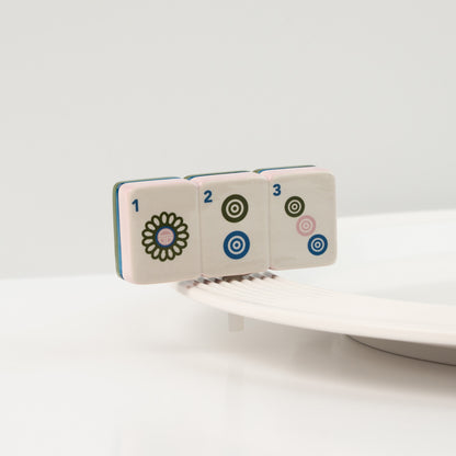 Set of four ceramic tiles with floral and geometric designs on a white background